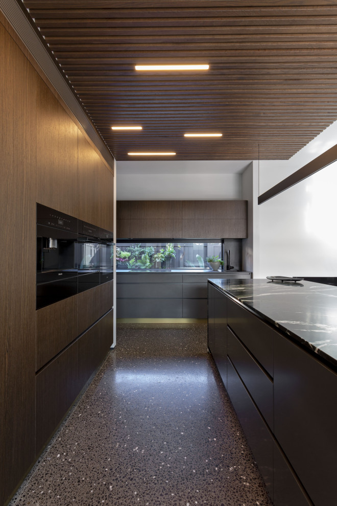Стильный дизайн: кухня-гостиная среднего размера в современном стиле с темными деревянными фасадами, мраморной столешницей, коричневым фартуком, черной техникой, островом, серым полом, черной столешницей и деревянным потолком - последний тренд