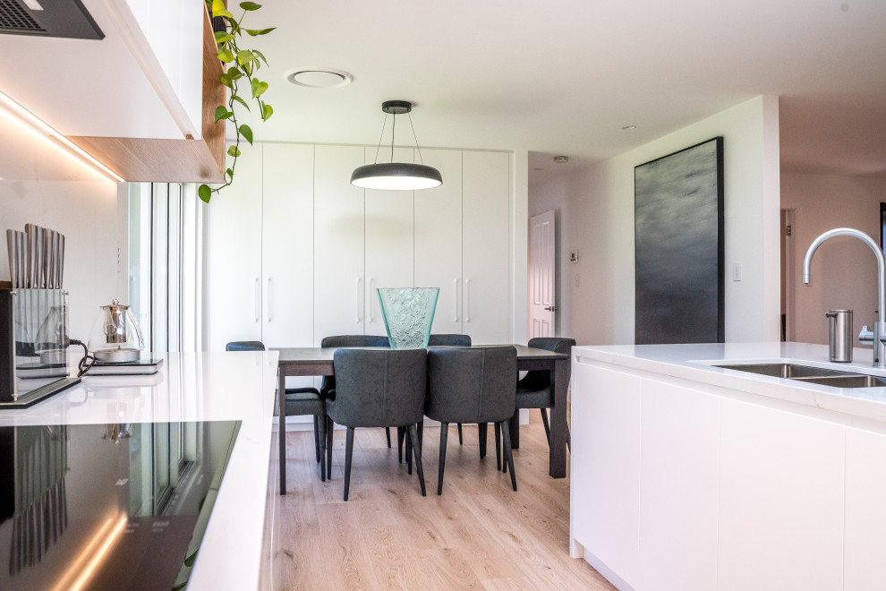 Inspiration pour une salle à manger ouverte sur le salon minimaliste de taille moyenne avec un mur blanc, sol en stratifié et un sol marron.