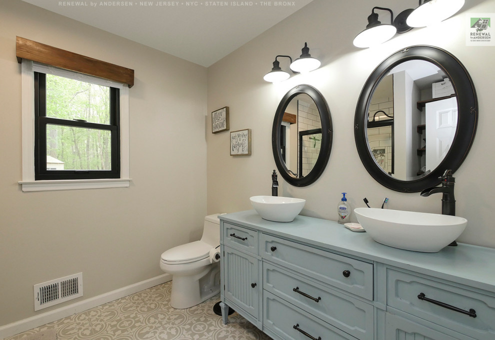 Стильный дизайн: главная ванная комната с синими фасадами, ванной в нише, душем над ванной, унитазом-моноблоком, белой плиткой, керамической плиткой, бежевыми стенами, настольной раковиной, столешницей из дерева, бежевым полом, душем с раздвижными дверями, синей столешницей, тумбой под две раковины, встроенной тумбой и сводчатым потолком - последний тренд