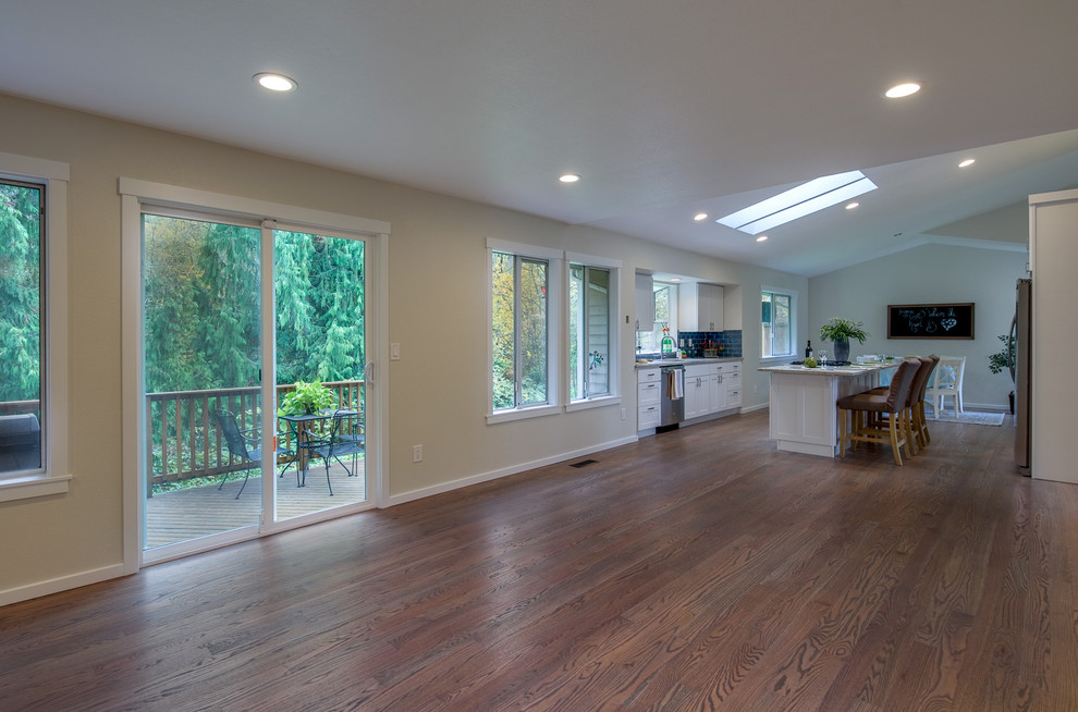 Example of a large transitional galley medium tone wood floor and brown floor open concept kitchen design in Seattle with an undermount sink, shaker cabinets, white cabinets, quartz countertops, blue backsplash, subway tile backsplash, stainless steel appliances, an island and multicolored countertops