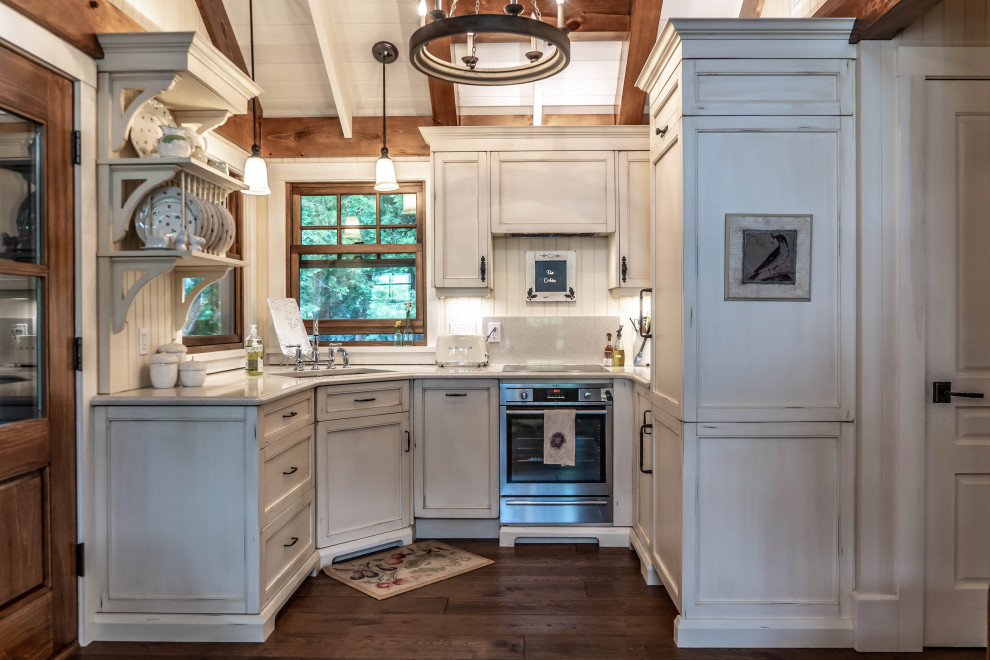Small country u-shaped kitchen in Other with a double-bowl sink, beaded inset cabinets, distressed cabinets, quartz benchtops, beige splashback, stone slab splashback, panelled appliances, dark hardwood floors, no island, brown floor and beige benchtop.