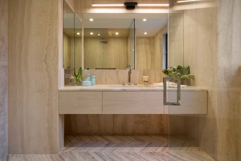 Photo of a mid-sized contemporary bathroom in New York with a drop-in tub, beige tile, stone slab and marble floors.