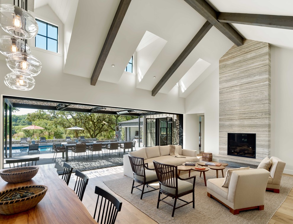 Example of a country open concept light wood floor and beige floor living room design in San Francisco with white walls