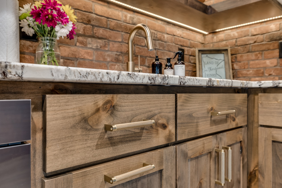Photo of a large classic l-shaped wet bar in Other with a submerged sink, shaker cabinets, medium wood cabinets, granite worktops, brown splashback, brick splashback, porcelain flooring, brown floors and white worktops.