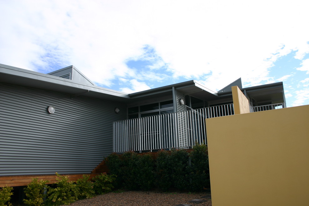 Mid-sized industrial split-level grey house exterior in Sydney with metal siding.