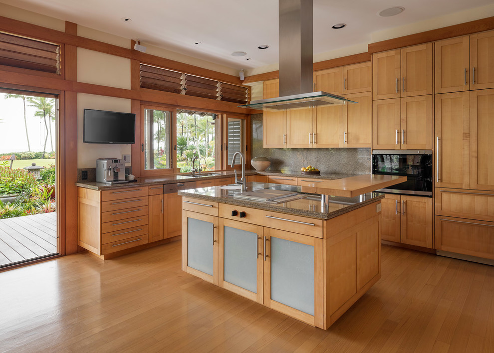 Large asian l-shaped kitchen in Hawaii with an undermount sink, recessed-panel cabinets, granite benchtops, brown splashback, stone slab splashback, panelled appliances, with island, brown benchtop, medium wood cabinets, medium hardwood floors and brown floor.