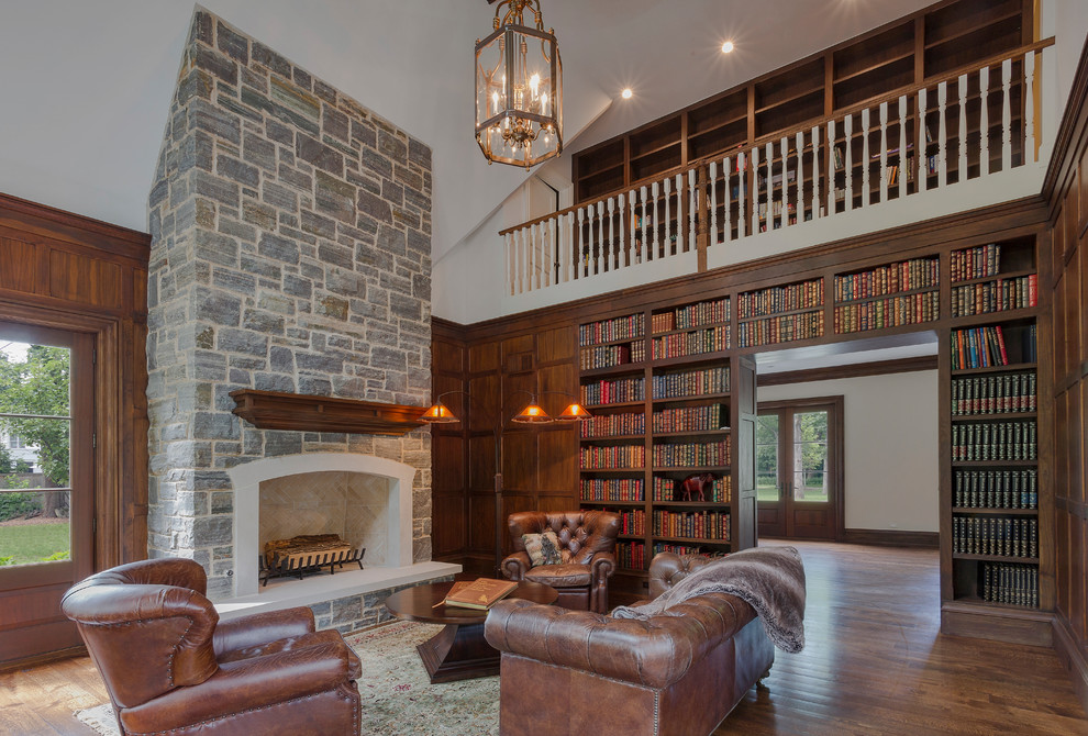 Large eclectic home office in Chicago with a library, brown walls, medium hardwood floors, a standard fireplace, a stone fireplace surround, a freestanding desk and brown floor.