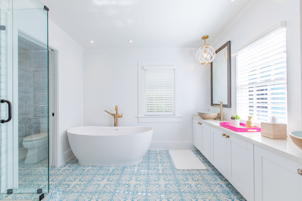 Design ideas for a tropical master bathroom in Miami with shaker cabinets, white cabinets, a freestanding tub, a corner shower, white walls, mosaic tile floors, a vessel sink, blue floor, a hinged shower door and an enclosed toilet.