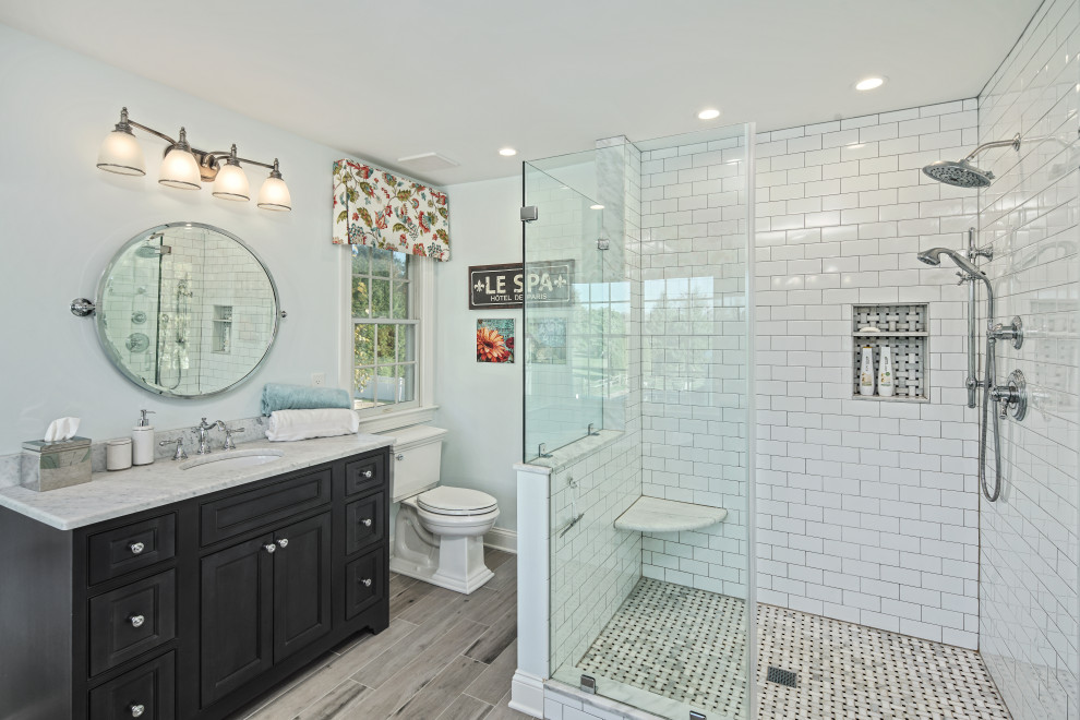 This is an example of a traditional bathroom in Philadelphia with beaded inset cabinets, black cabinets, a corner shower, white tile, subway tile, grey walls, wood-look tile, an undermount sink, grey floor, a hinged shower door, white benchtops, a niche, a single vanity and a freestanding vanity.