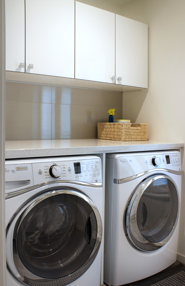 Photo of a small contemporary galley dedicated laundry room in New York with a drop-in sink, flat-panel cabinets, white cabinets, granite benchtops, grey walls, porcelain floors and a side-by-side washer and dryer.