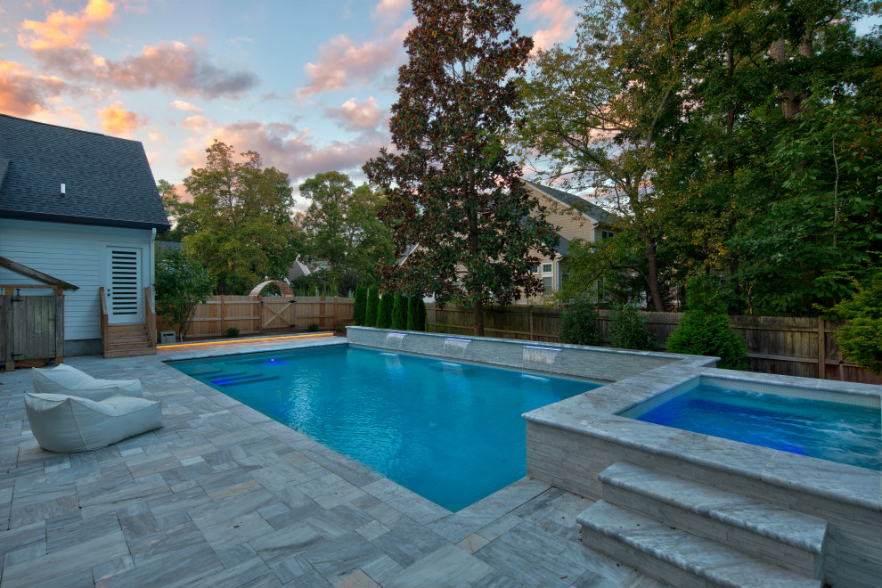 Ispirazione per una grande piscina design rettangolare dietro casa con una vasca idromassaggio e pavimentazioni in pietra naturale