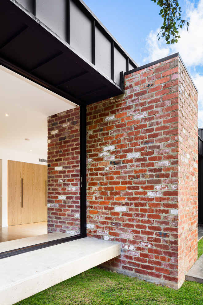 Large contemporary one-storey brick black house exterior in Melbourne with a flat roof and a metal roof.