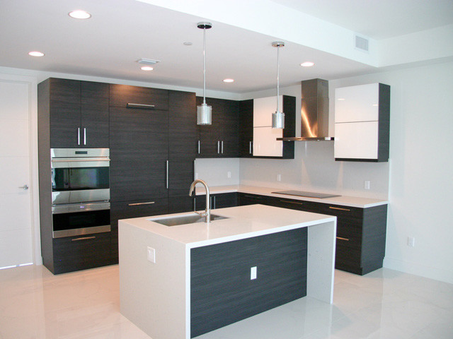 Design ideas for a mid-sized contemporary l-shaped kitchen in Miami with an undermount sink, flat-panel cabinets, black cabinets, quartzite benchtops, panelled appliances, with island and grey floor.