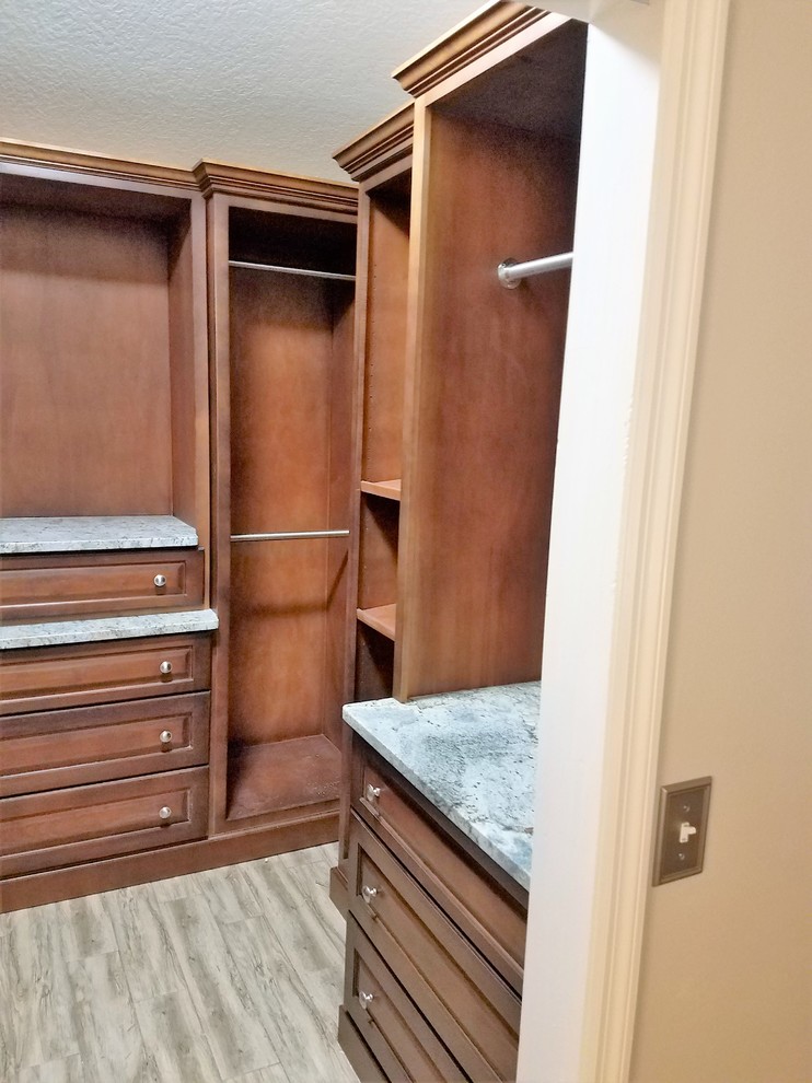 Inspiration for a mid-sized traditional gender-neutral walk-in wardrobe in Orlando with raised-panel cabinets, medium wood cabinets and porcelain floors.