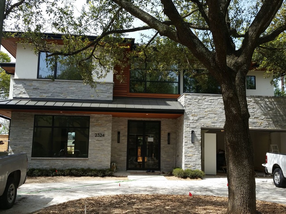 Photo of a large contemporary two-storey grey exterior in Houston with stone veneer.