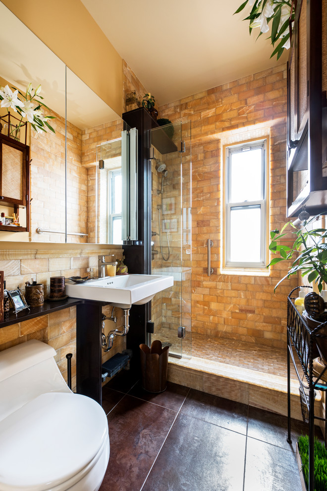 Photo of a small mediterranean bathroom in New York with an alcove shower, a two-piece toilet, stone tile, multi-coloured walls, ceramic floors, a wall-mount sink and brown tile.