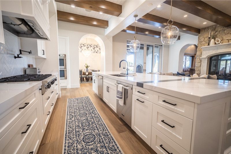 This contemporary home remodel was so fun for the MFD Team! This white kitchen features exposed wood beams, medium washed hardwood flooring, and stainless steel appliances. The open concept design spa