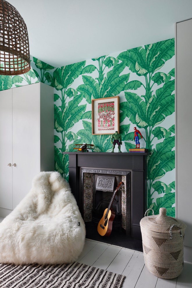 This is an example of a small eclectic bedroom in London with green walls, light hardwood floors, a standard fireplace and a metal fireplace surround.