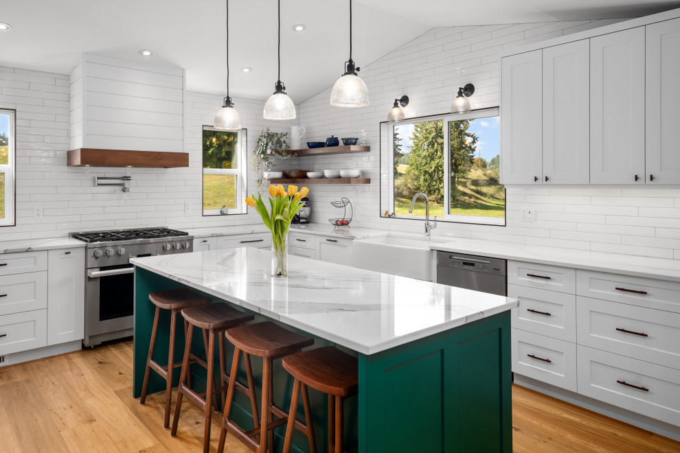 Inspiration for a farmhouse u-shaped laminate floor and beige floor kitchen remodel in Vancouver with a farmhouse sink, white cabinets, white backsplash, porcelain backsplash, stainless steel appliances, an island and white countertops