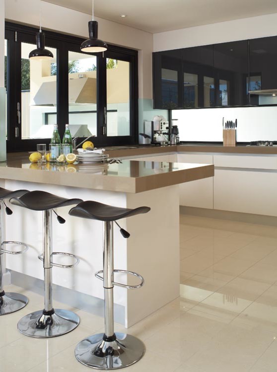 Inspiration for a large modern u-shaped eat-in kitchen in Sydney with a double-bowl sink, flat-panel cabinets, white cabinets, solid surface benchtops, glass sheet splashback, stainless steel appliances, porcelain floors and a peninsula.