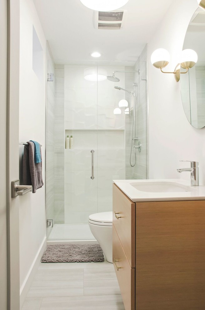Design ideas for a mid-sized contemporary 3/4 bathroom in Vancouver with flat-panel cabinets, medium wood cabinets, an alcove shower, a two-piece toilet, white tile, porcelain tile, white walls, porcelain floors, an undermount sink, engineered quartz benchtops, beige floor and a hinged shower door.