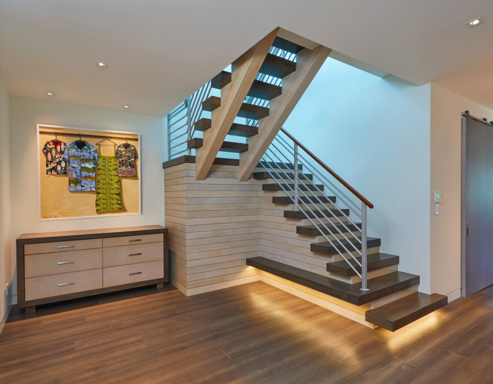 This is an example of a mid-sized tropical wood u-shaped staircase in Hawaii with open risers, mixed railing and wood walls.