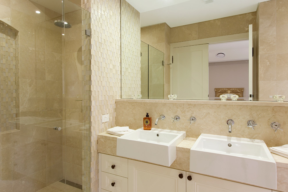 This is an example of a transitional bathroom in Sydney with a vessel sink, shaker cabinets, white cabinets, a double shower, beige tile and stone tile.