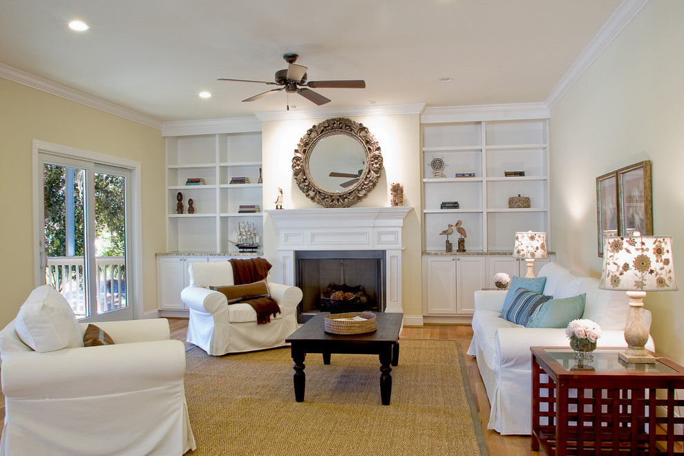 Photo of a mid-sized beach style formal enclosed living room in Charleston with yellow walls, light hardwood floors, a standard fireplace, a wood fireplace surround and no tv.
