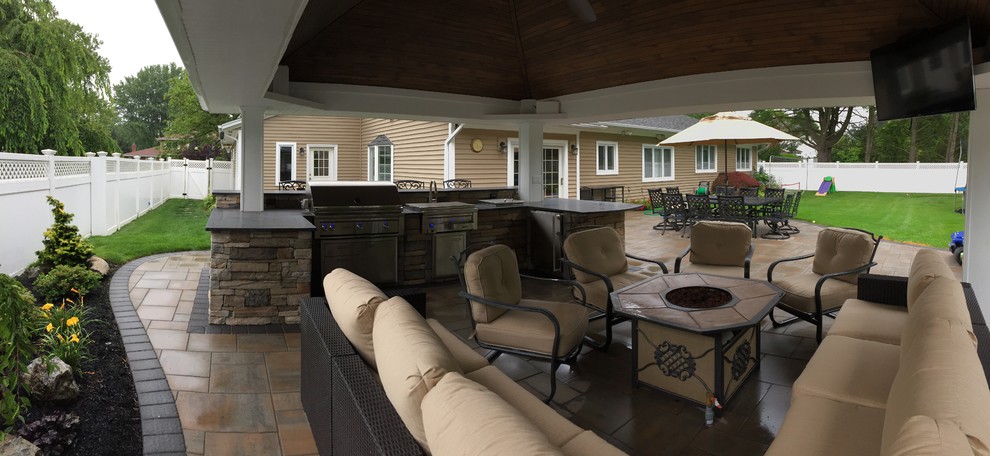 This is an example of a large traditional backyard patio in New York with an outdoor kitchen, concrete pavers and a gazebo/cabana.