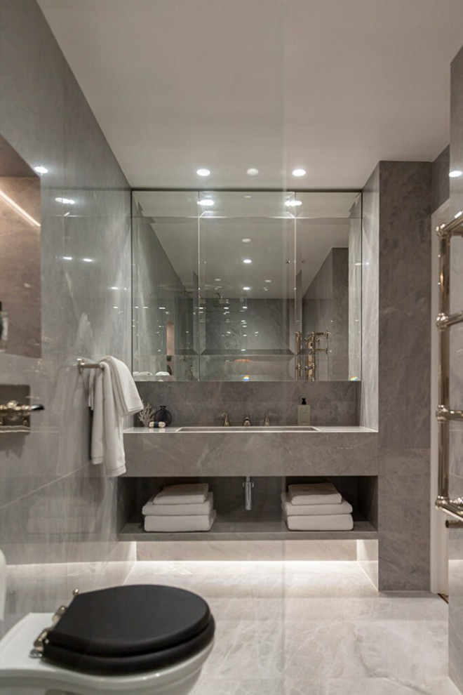 Photo of a large modern 3/4 bathroom in London with grey cabinets, a drop-in tub, a shower/bathtub combo, gray tile, glass tile, grey walls, ceramic floors, a drop-in sink, stainless steel benchtops, grey floor, a hinged shower door, brown benchtops, a single vanity, a floating vanity, wood, decorative wall panelling, an urinal and open cabinets.