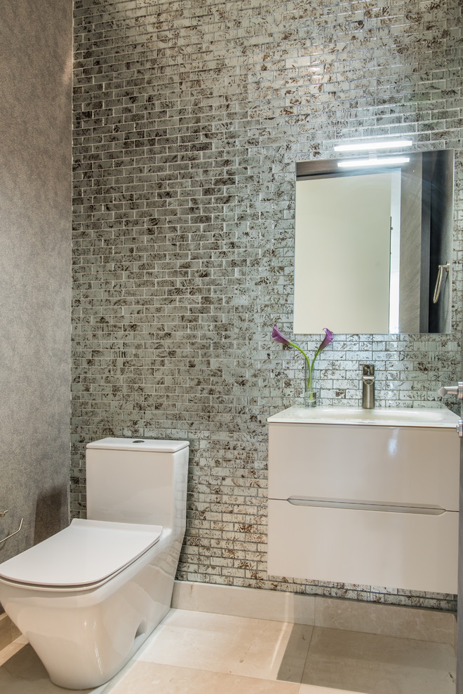 Photo of a mid-sized transitional 3/4 bathroom with furniture-like cabinets, beige cabinets, a two-piece toilet, multi-coloured tile, glass tile, multi-coloured walls, marble floors, an integrated sink, glass benchtops and beige floor.