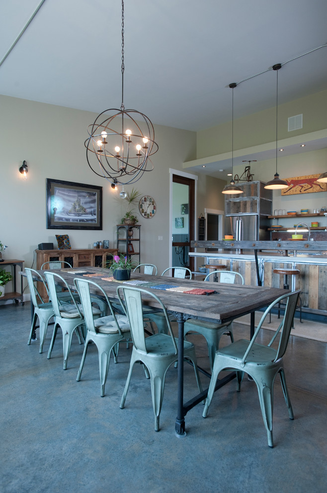 Photo of a large industrial open plan dining in Other with grey walls, concrete floors and a stone fireplace surround.