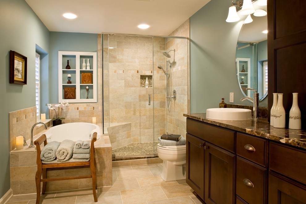 Mid-sized traditional master bathroom in Baltimore with recessed-panel cabinets, dark wood cabinets, a drop-in tub, an alcove shower, a two-piece toilet, blue walls, a vessel sink, brown tile, travertine, travertine floors, granite benchtops, brown floor and a hinged shower door.