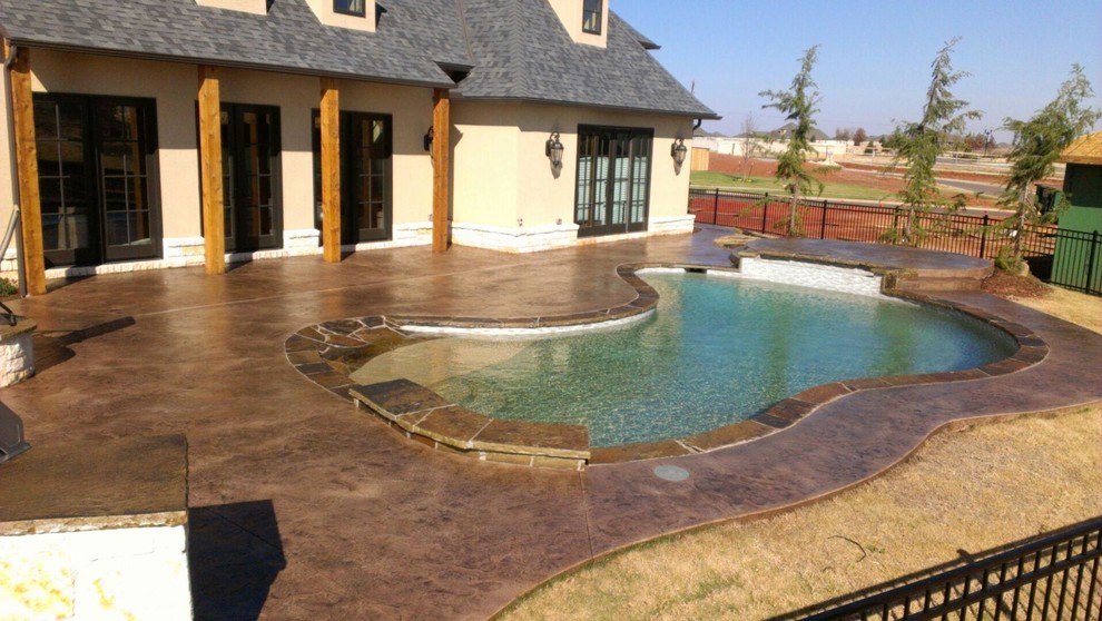 Inspiration for a large traditional backyard kidney-shaped pool in Oklahoma City with concrete slab.