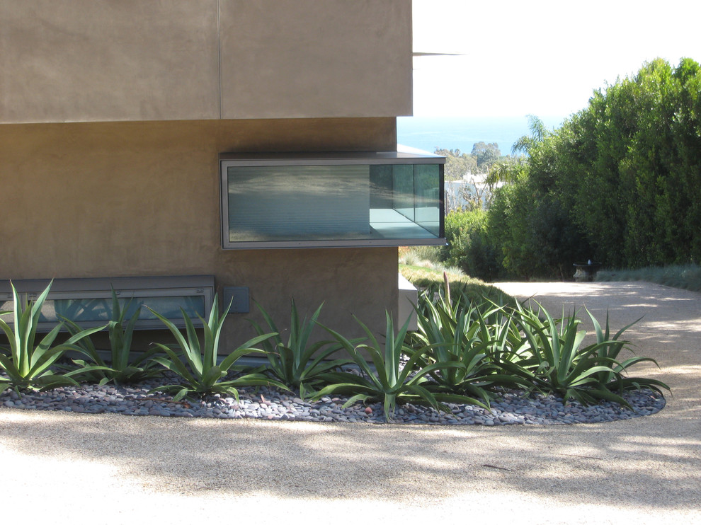 Photo of a mid-sized modern front yard partial sun driveway for spring in Los Angeles with gravel.