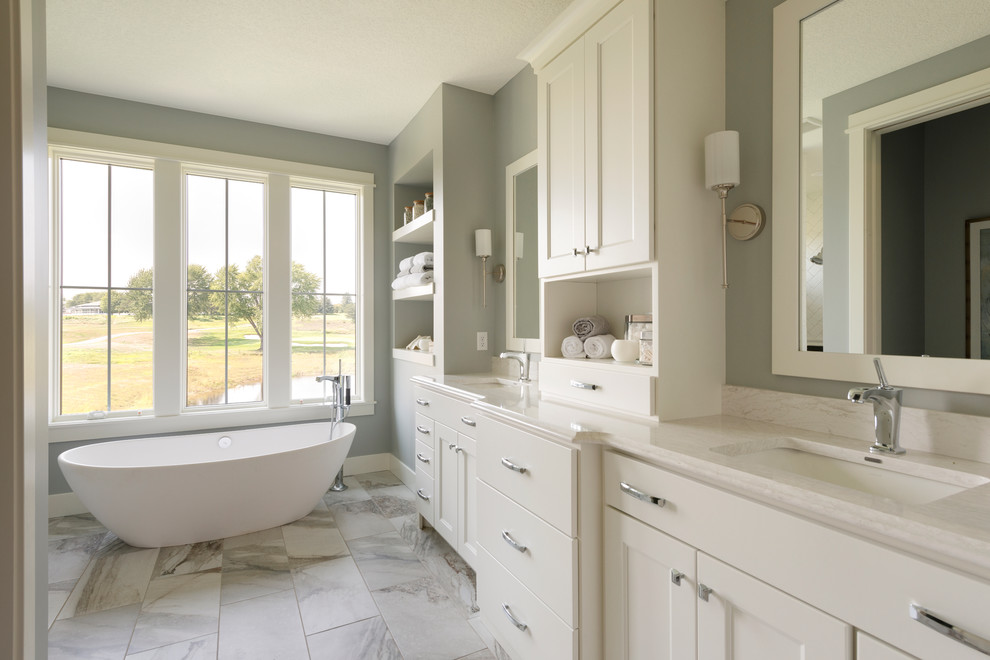 Transitional master bathroom in Minneapolis with shaker cabinets, beige cabinets, a freestanding tub, grey walls, an undermount sink, grey floor and beige benchtops.