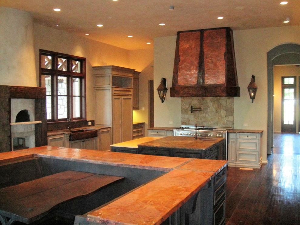 Photo of a large country u-shaped eat-in kitchen in Atlanta with a farmhouse sink, distressed cabinets, limestone benchtops, beige splashback, stone tile splashback, stainless steel appliances, dark hardwood floors and multiple islands.