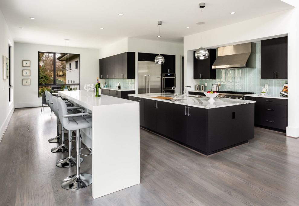 Contemporary galley kitchen in DC Metro with flat-panel cabinets, black cabinets, blue splashback, glass tile splashback, stainless steel appliances, dark hardwood floors, multiple islands, brown floor and white benchtop.