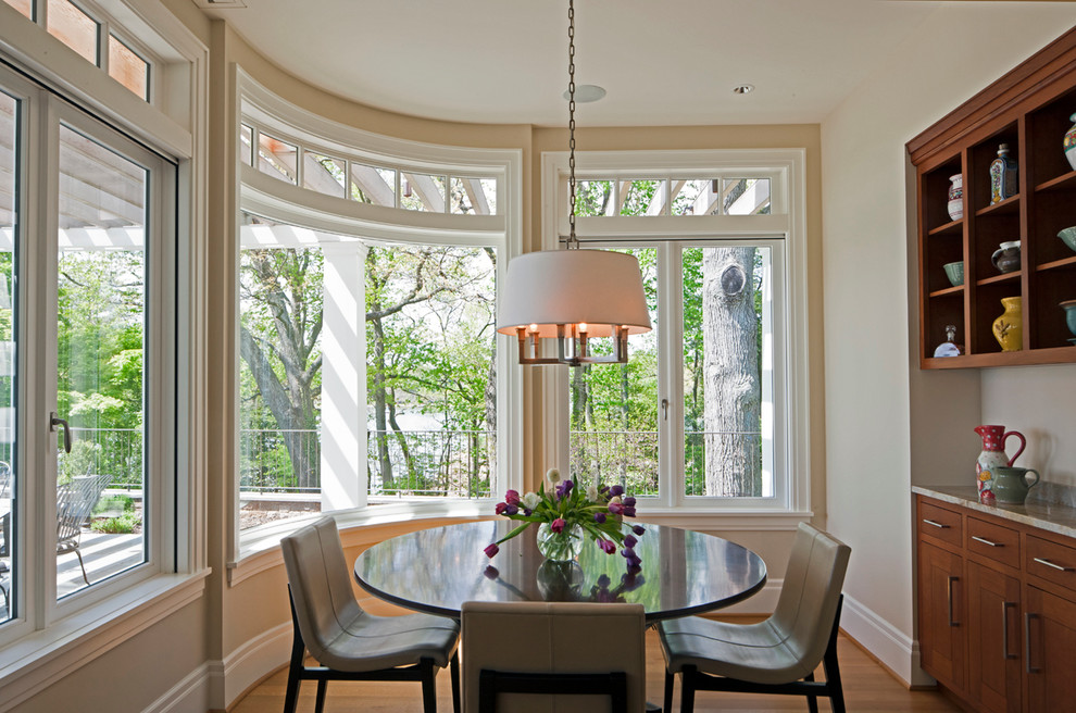 This is an example of a traditional dining room in Baltimore with beige walls and light hardwood floors.