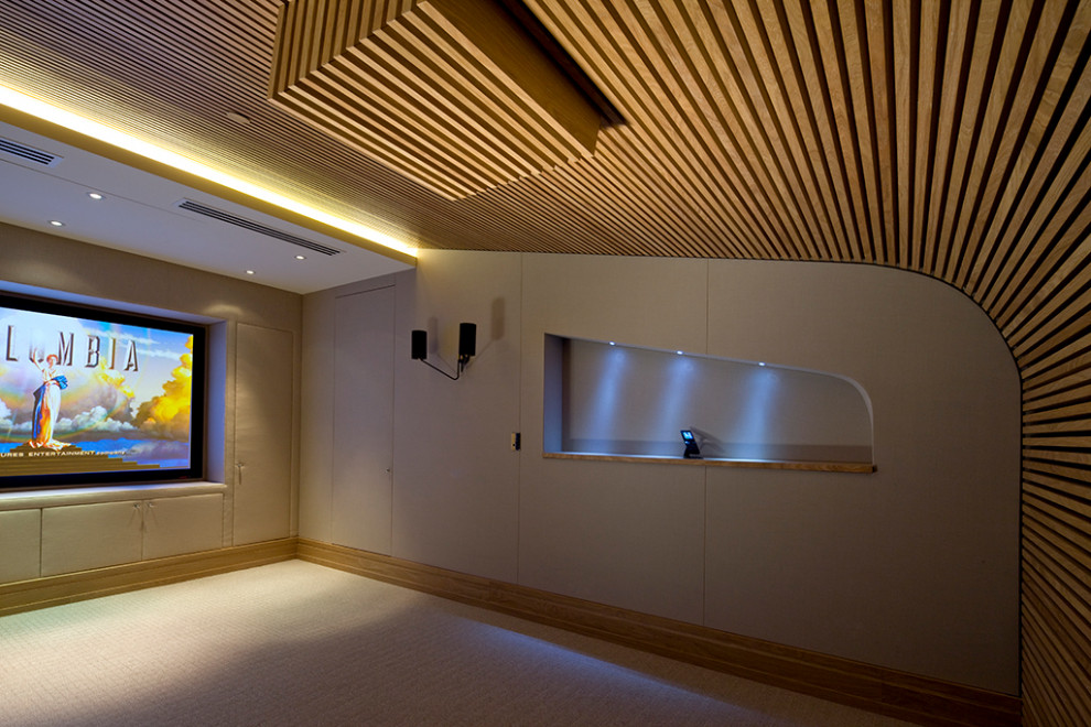 Mid-sized contemporary enclosed home theatre in London with beige walls, carpet, a projector screen and beige floor.
