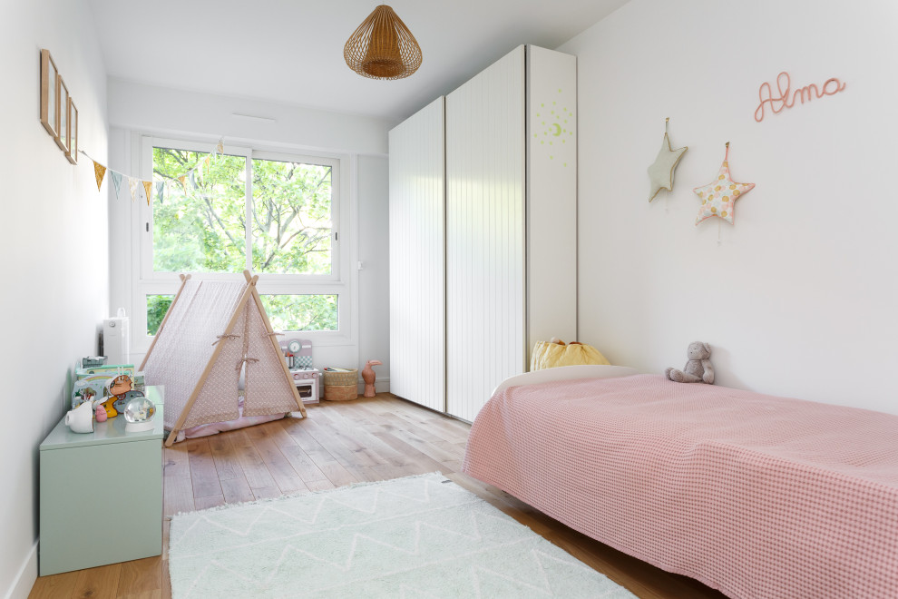 Photo of a mid-sized scandinavian kids' bedroom for kids 4-10 years old and girls in Paris with white walls, light hardwood floors and beige floor.