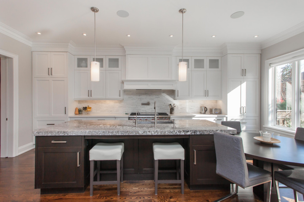 Modern inredning av ett stort grå grått kök, med en nedsänkt diskho, luckor med infälld panel, vita skåp, bänkskiva i kalksten, vitt stänkskydd, stänkskydd i marmor, rostfria vitvaror, mellanmörkt trägolv, en köksö och brunt golv