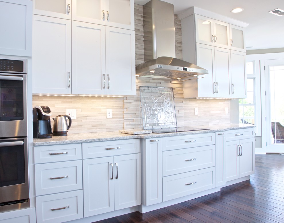 Eat-in kitchen - mid-sized transitional galley eat-in kitchen idea with white cabinets, granite countertops, beige backsplash, stone tile backsplash and stainless steel appliances