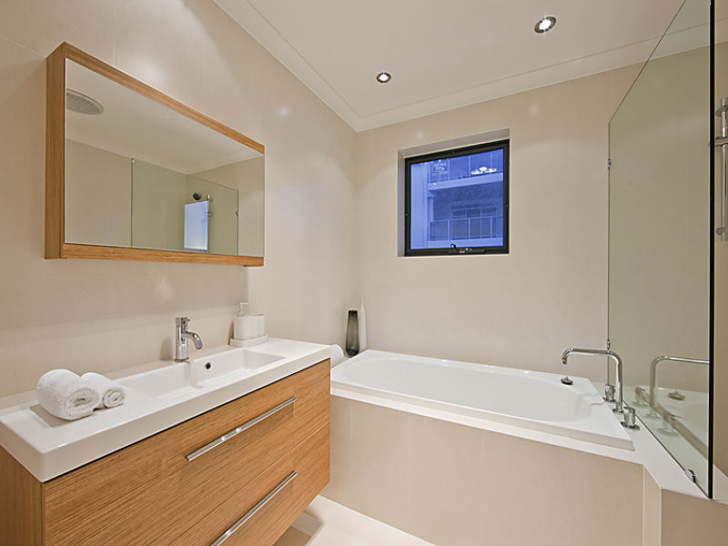 Contemporary bathroom in Perth with flat-panel cabinets, medium wood cabinets, a corner tub, a corner shower, beige tile, porcelain tile, porcelain floors, a trough sink, beige floor and an open shower.