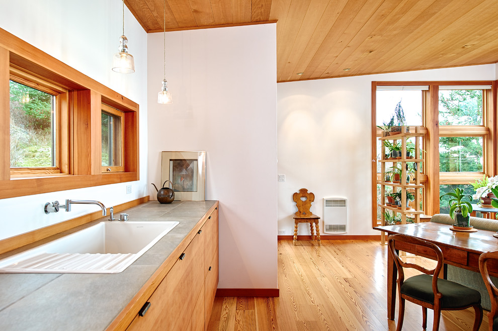 Inspiration for a small modern single-wall eat-in kitchen in Seattle with flat-panel cabinets, light wood cabinets, tile benchtops, light hardwood floors, no island, a drop-in sink, stainless steel appliances, brown floor and grey benchtop.