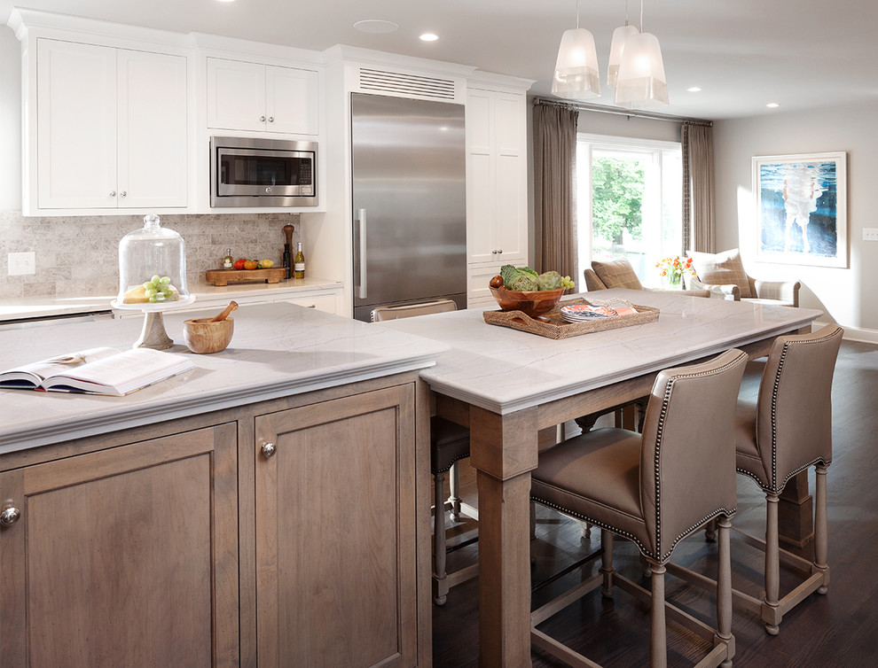 Design ideas for a large transitional single-wall eat-in kitchen in Orlando with shaker cabinets, white cabinets, marble benchtops, beige splashback, stone tile splashback, stainless steel appliances, medium hardwood floors and with island.
