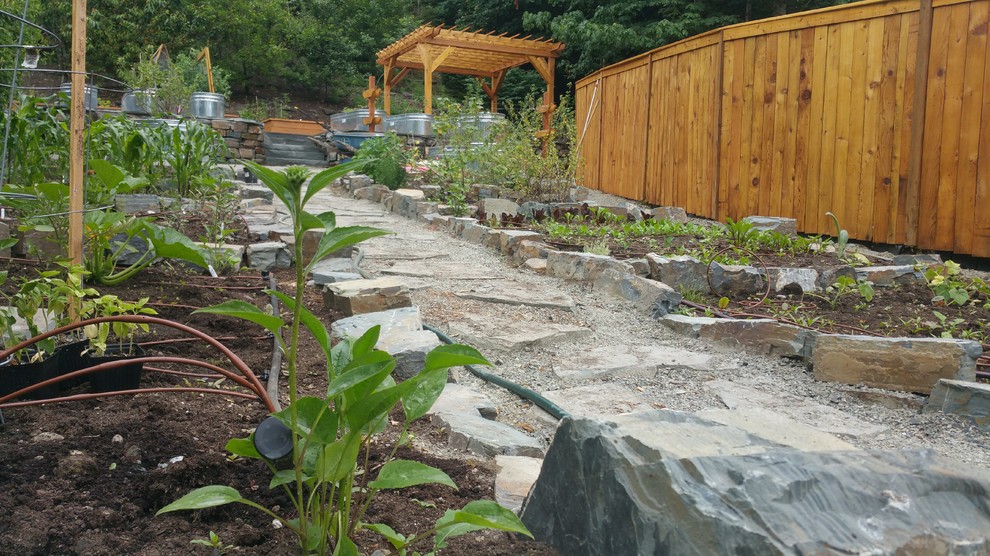 This is an example of a mid-sized country backyard partial sun formal garden for summer in Seattle with a vegetable garden and natural stone pavers.