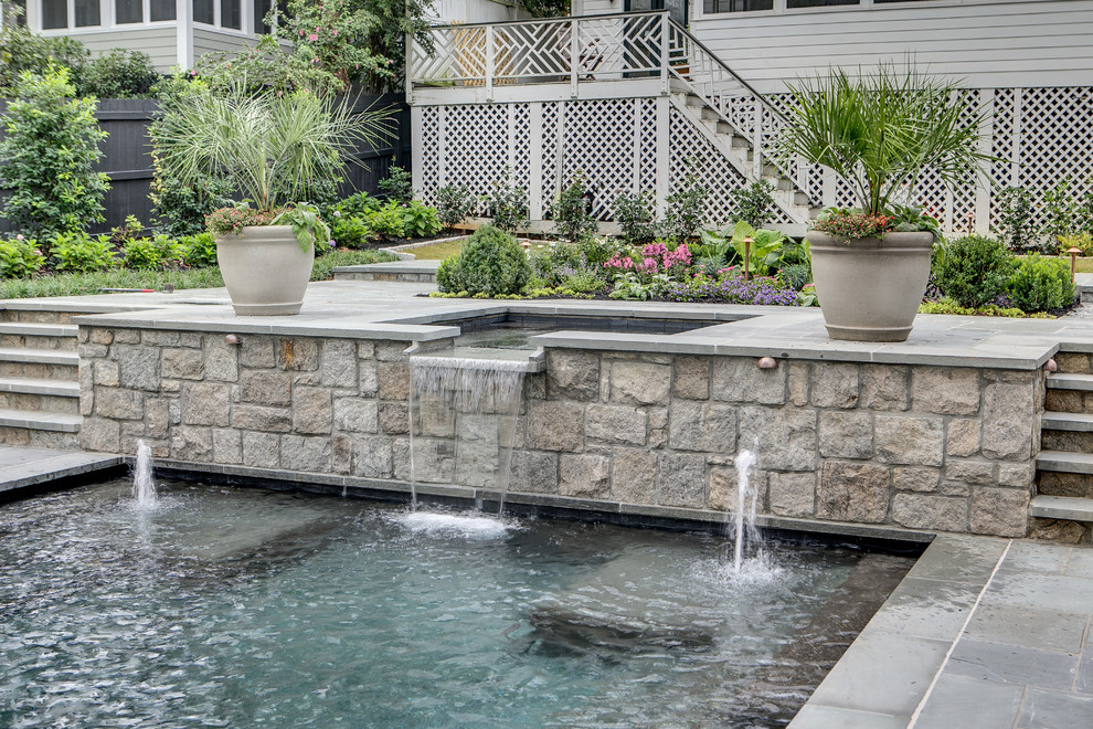 This is an example of a large contemporary backyard custom-shaped infinity pool in Atlanta with a water feature and natural stone pavers.