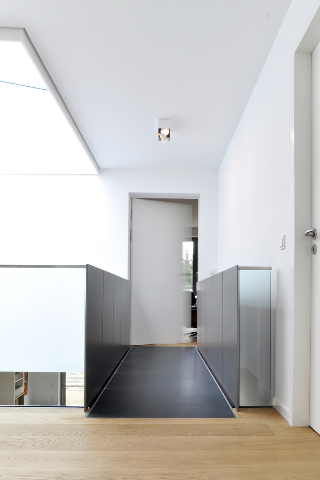 This is an example of a contemporary hallway in Munich with white walls and light hardwood floors.