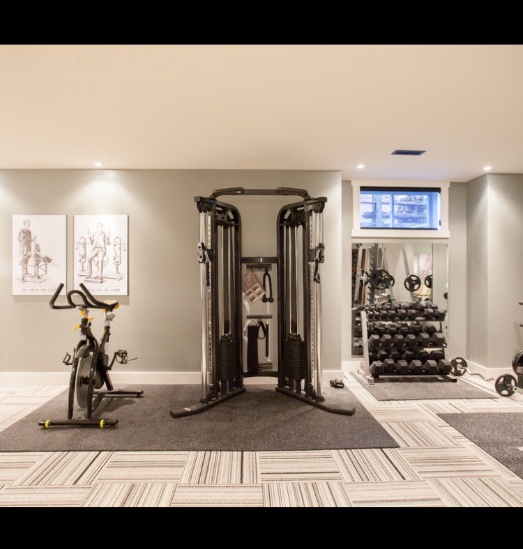 Large modern home weight room in New York with grey walls and carpet.